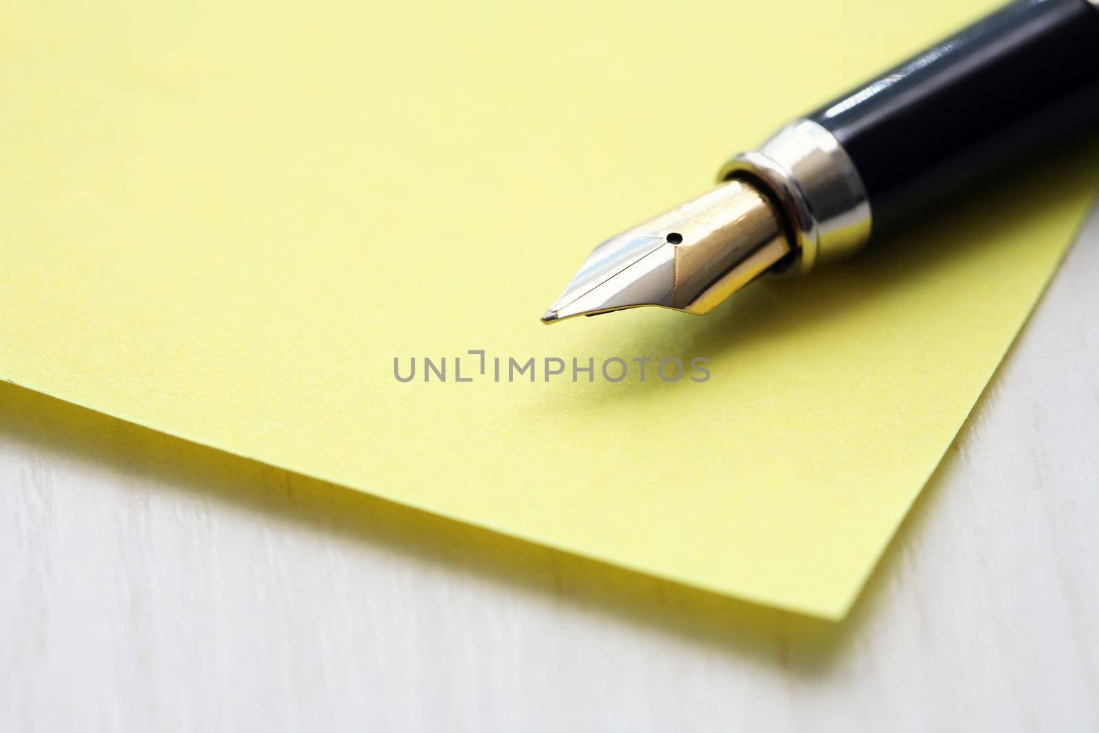 Closeup of nice vintage ink pen on empty yellow paper