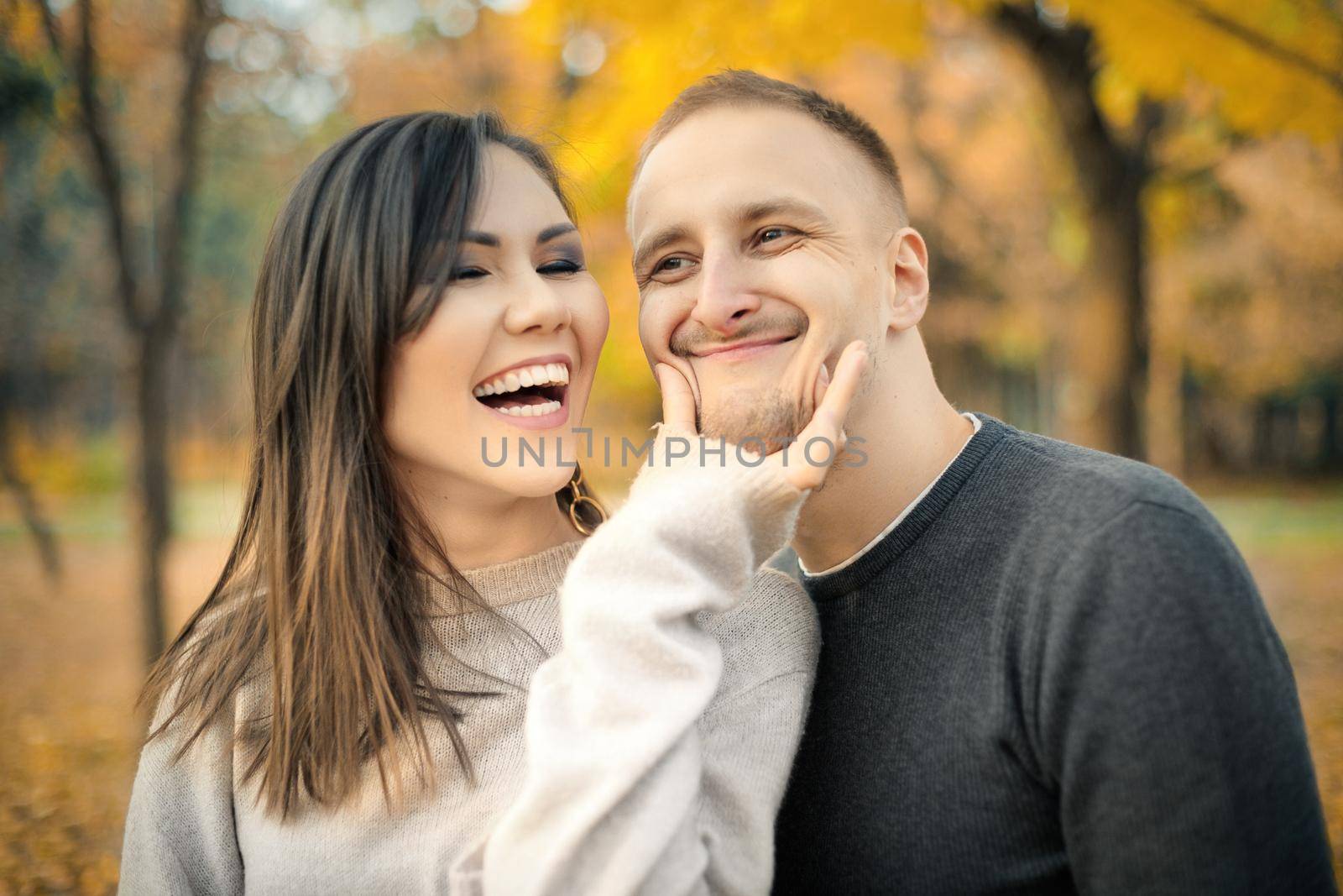 Outdoor portrait of interethnic couple in autumn park having fun together.