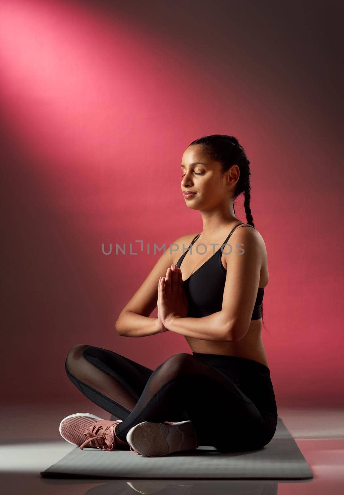 Focus on you completely for a change. Studio shot of a sporty young woman meditating against a red background. by YuriArcurs
