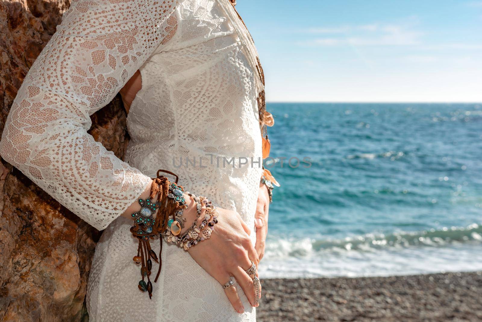 Woman in bohemian clothing on beach at sunset. Boho style for fashionable look on resort. Middle aged well looking woman in white dress and boho style braclets. Summer fashion by panophotograph