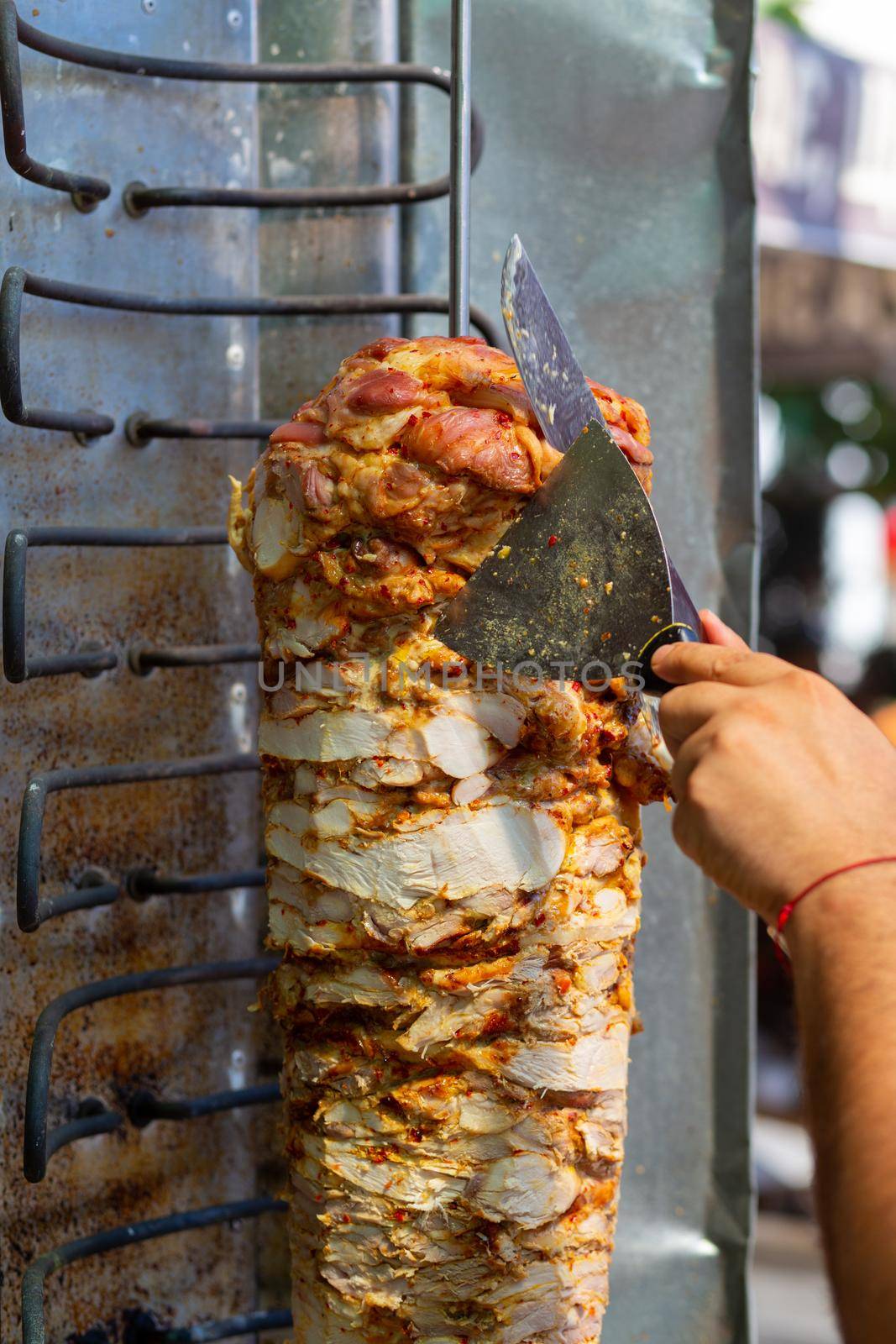 Chef cutting with doner knife Traditional Turkish Doner Kebab meat. Shawarma or gyros. Turkish, greek or middle eastern arab style chicken doner kebab food.