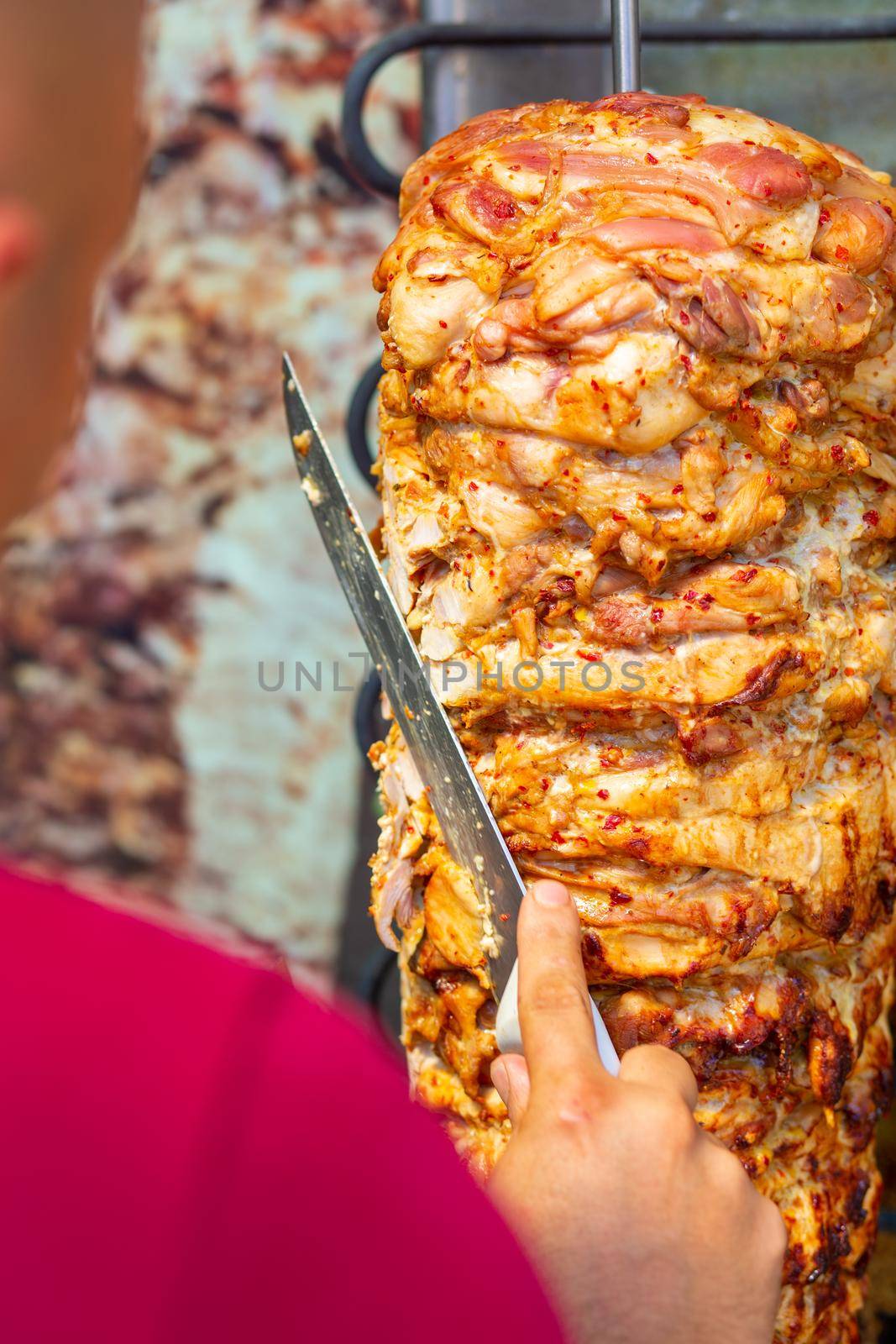 Chef cutting with doner knife Traditional Turkish Doner Kebab meat. Shawarma or gyros. Turkish, greek or middle eastern arab style chicken doner kebab food.