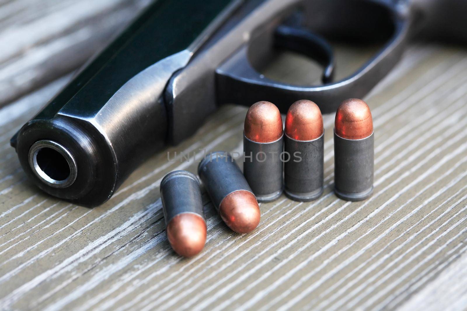 Handgun cartridges closeup on old wooden background near pistol