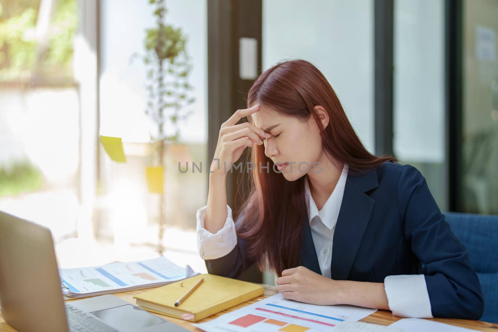 Portrait of an Asian businesswoman showing a headache from depression by Manastrong