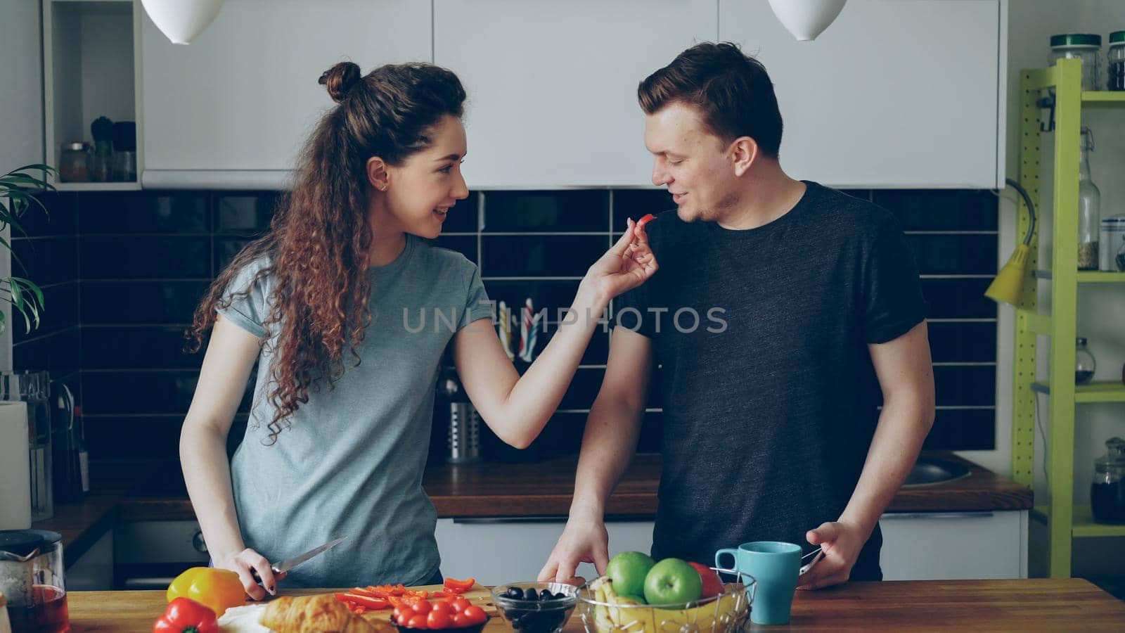 positive young caucasian couple have fun in kitchen at home by silverkblack