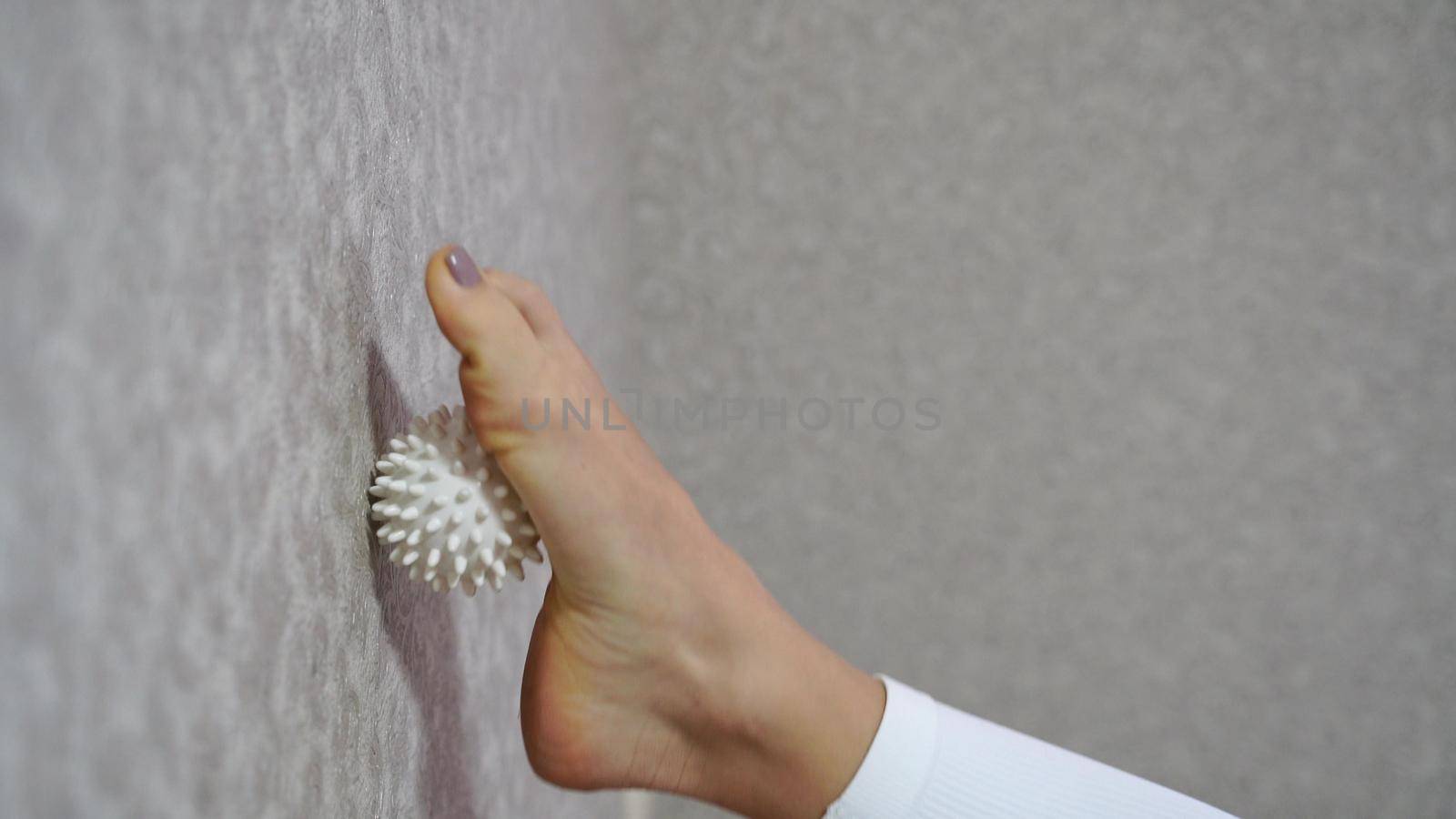 Close-up, a woman doing a foot massage with a special massage ball. The concept of prevention and treatment of flat feet. by Matiunina