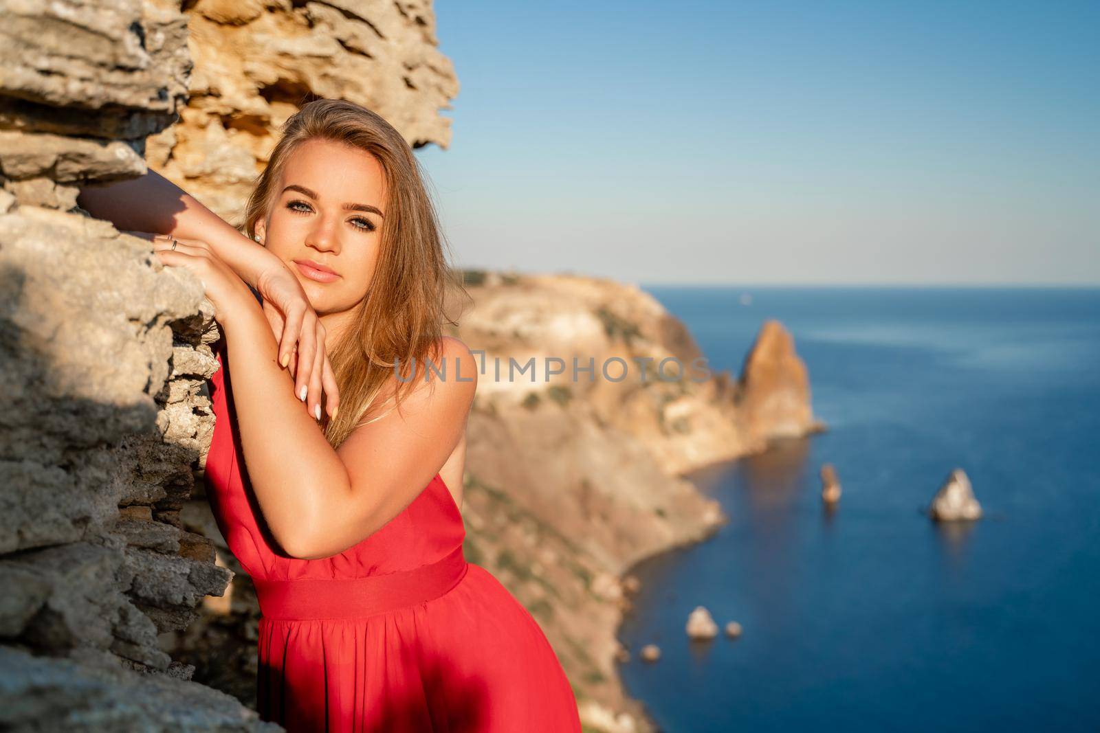 A woman in a red flying dress fluttering in the wind, against the backdrop of the sea. by Matiunina