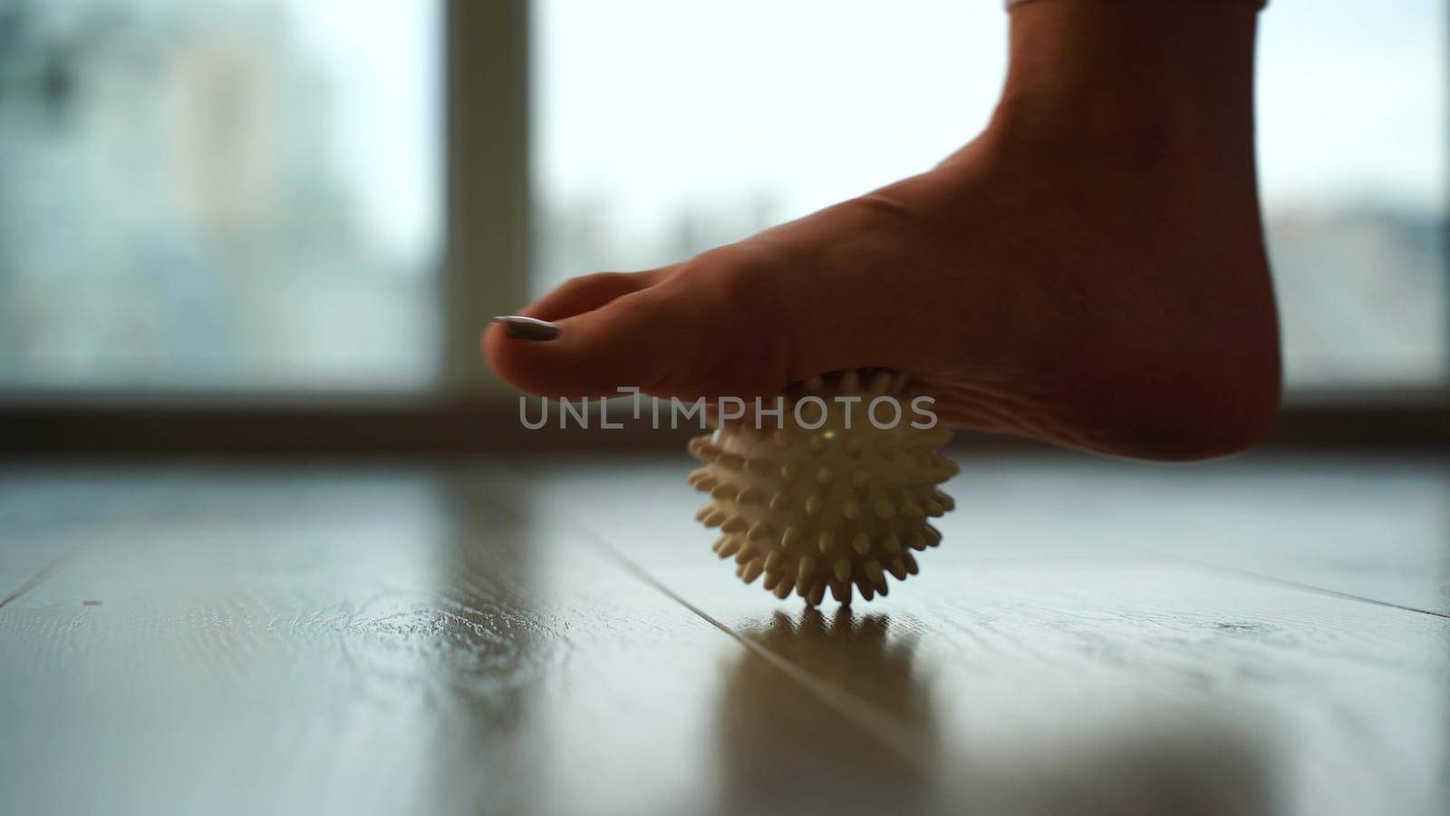 Close-up, a woman doing a foot massage with a special massage ball. The concept of prevention and treatment of flat feet