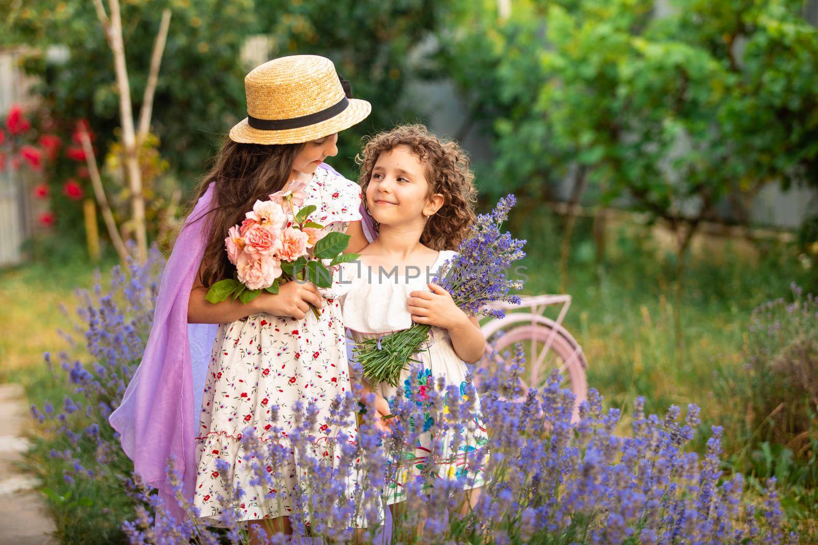 Romantic portrait o charming sisters in straw hats in lavender bushes