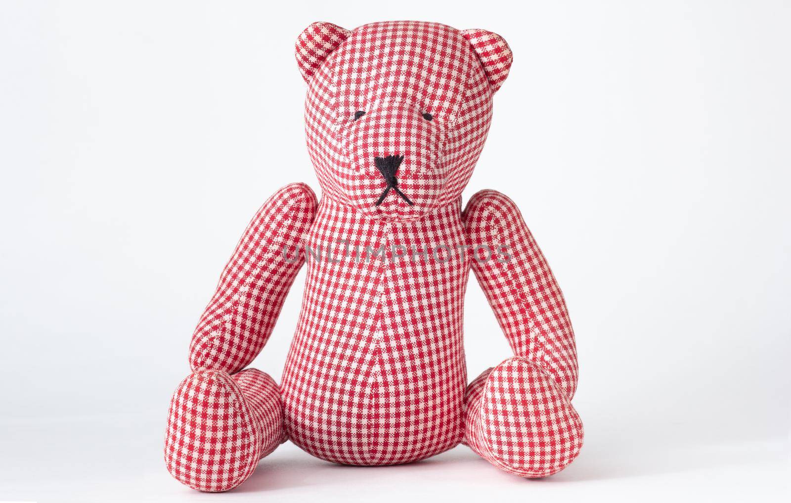Isolated handmade check drapery red and white teddy bear toy made from plaid material on white background