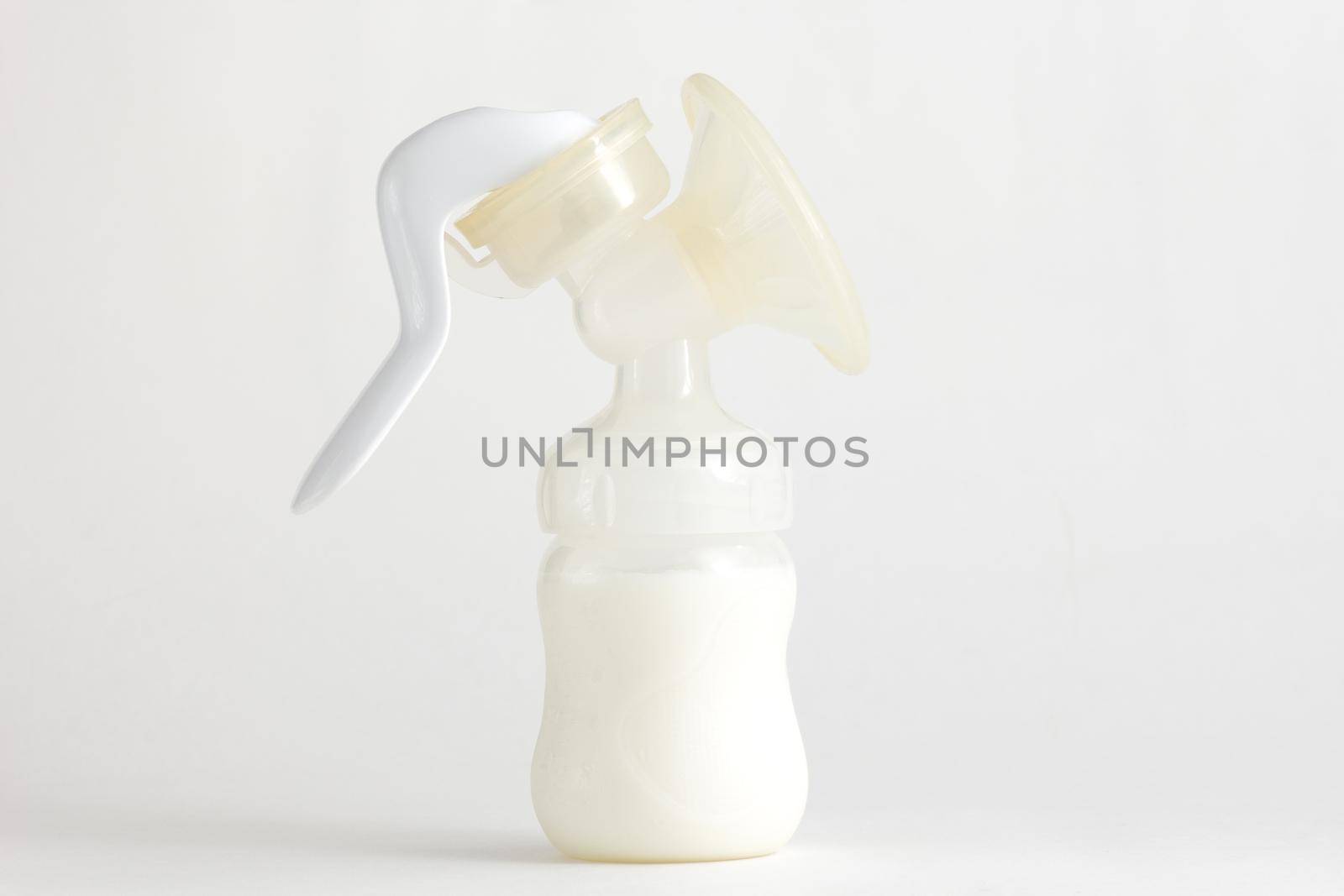 Isolated baby manual breast pump full of milk on white background