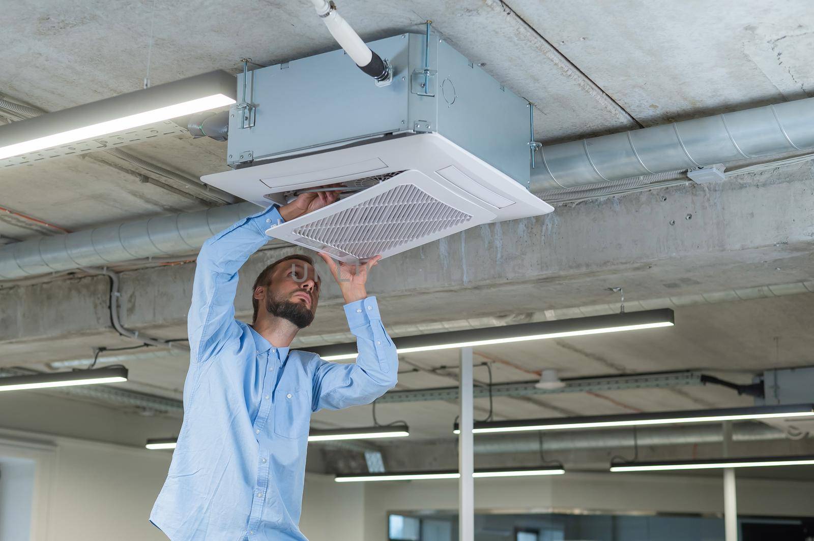 Caucasian bearded man repairing the air conditioner in the office. by mrwed54