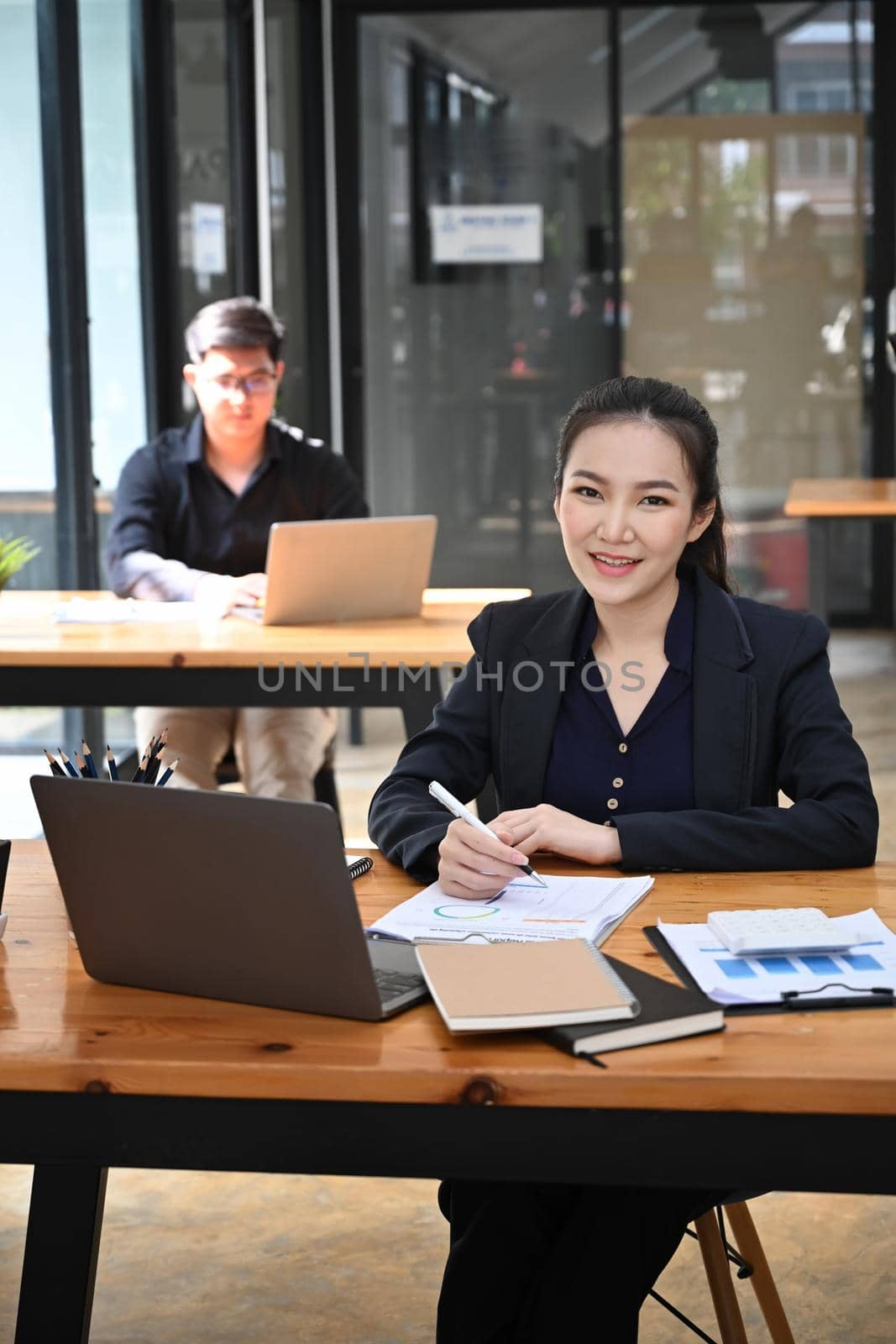 Portrait of attractive businesswoman sitting in office with her colleague. by prathanchorruangsak