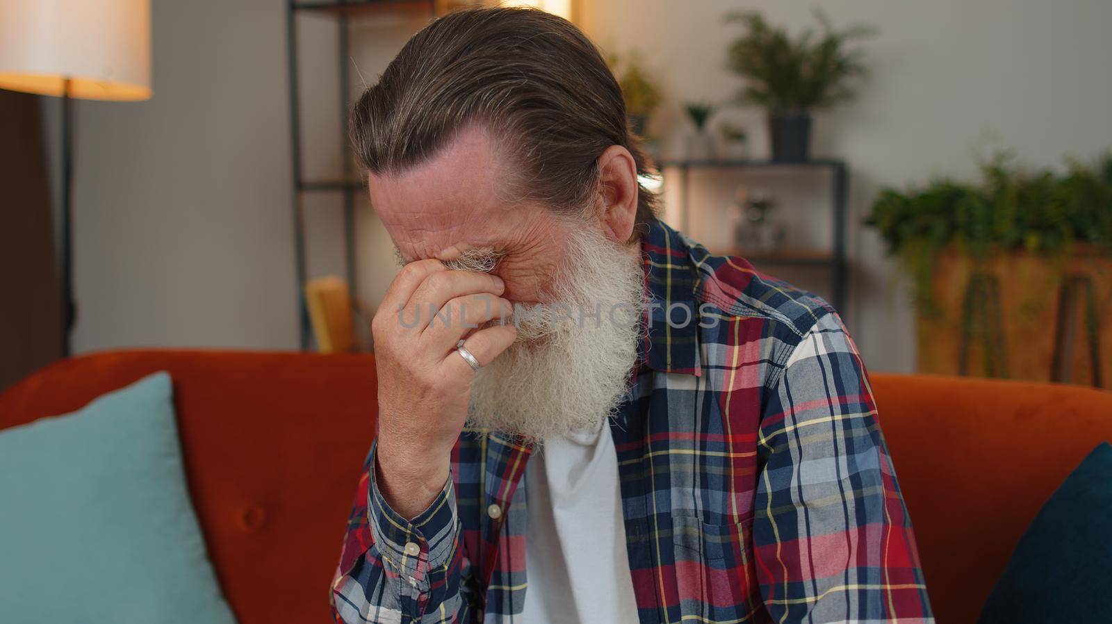 Upset disappointed senior grandfather man wipes tears and cries from despair, being sad because of unfair situation, unrequited love. Problem, break up, depressed feeling bad annoyed, burnout at home