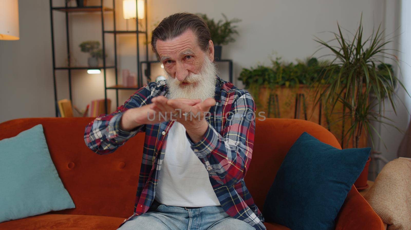 Cheerful rich senior old grandfather man showing wasting or throwing money around hand gesture, more tips earnings, big profit, win lottery, body language, share. Elderly guy at home in room on sofa