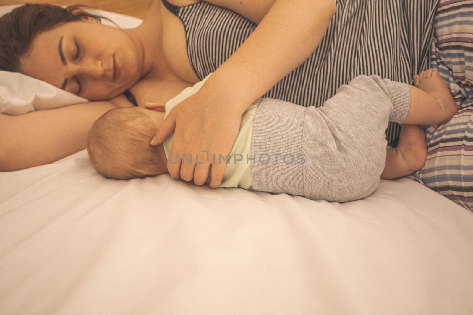 Mother and newborn baby sleep in the bed together