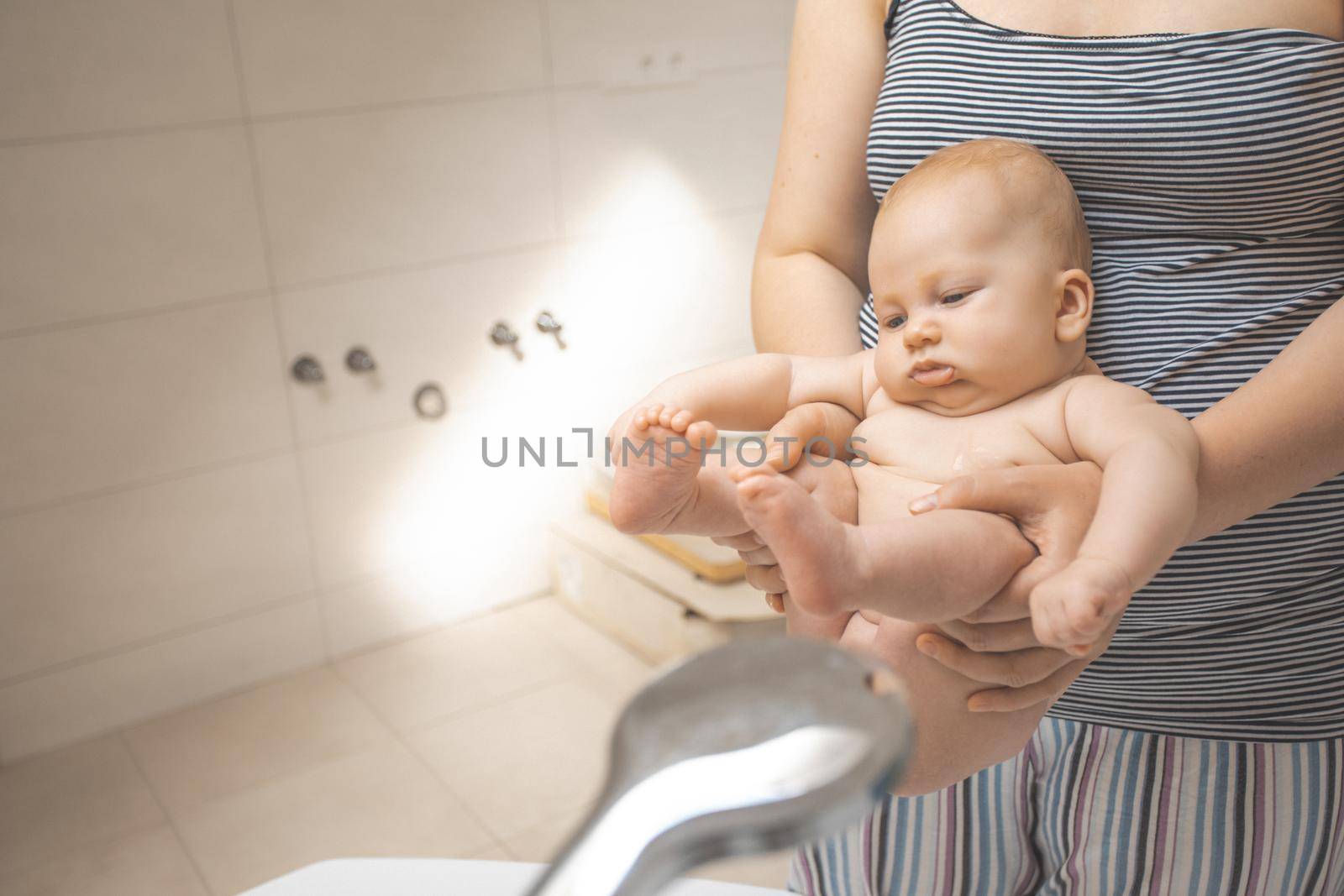 Mother washes her baby after stool at the shower by oksix