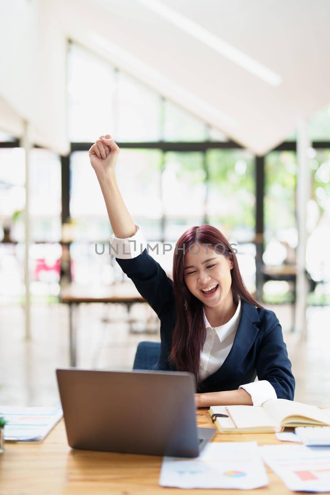 cheerful Asian celebrating her victory online with her laptop by Manastrong
