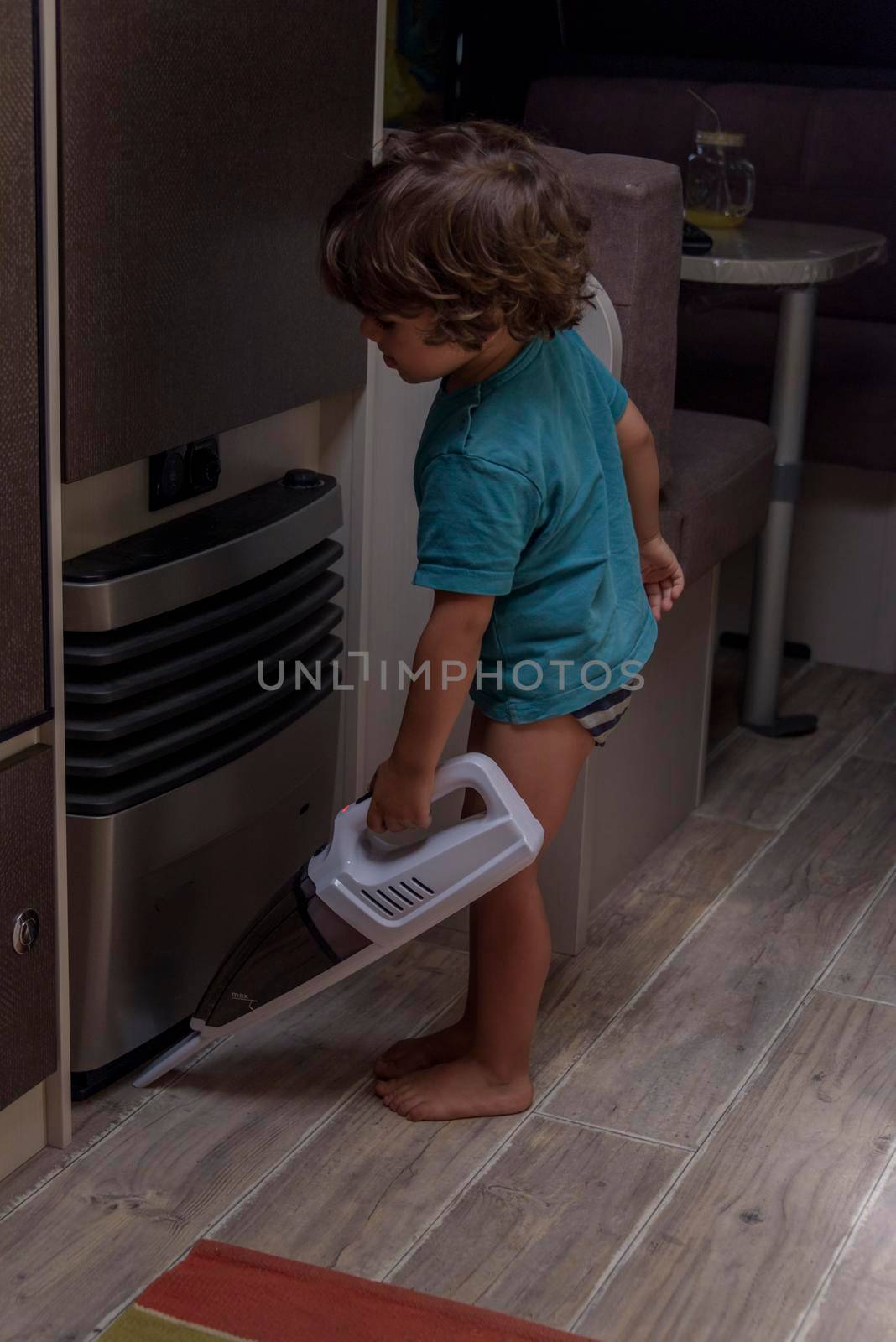 A sweet little boy vacuums the caravan while on vacation. A cute boy is cleaning the caravan. by jbruiz78