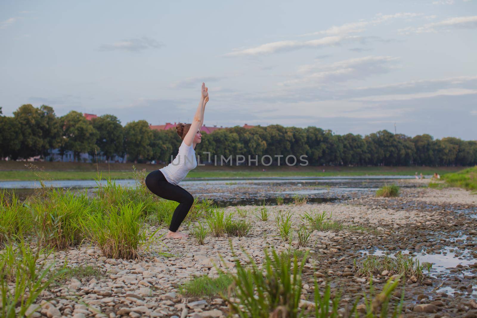 Yoga classes in nature. Young woman does yoga on rocks, near a river flows
