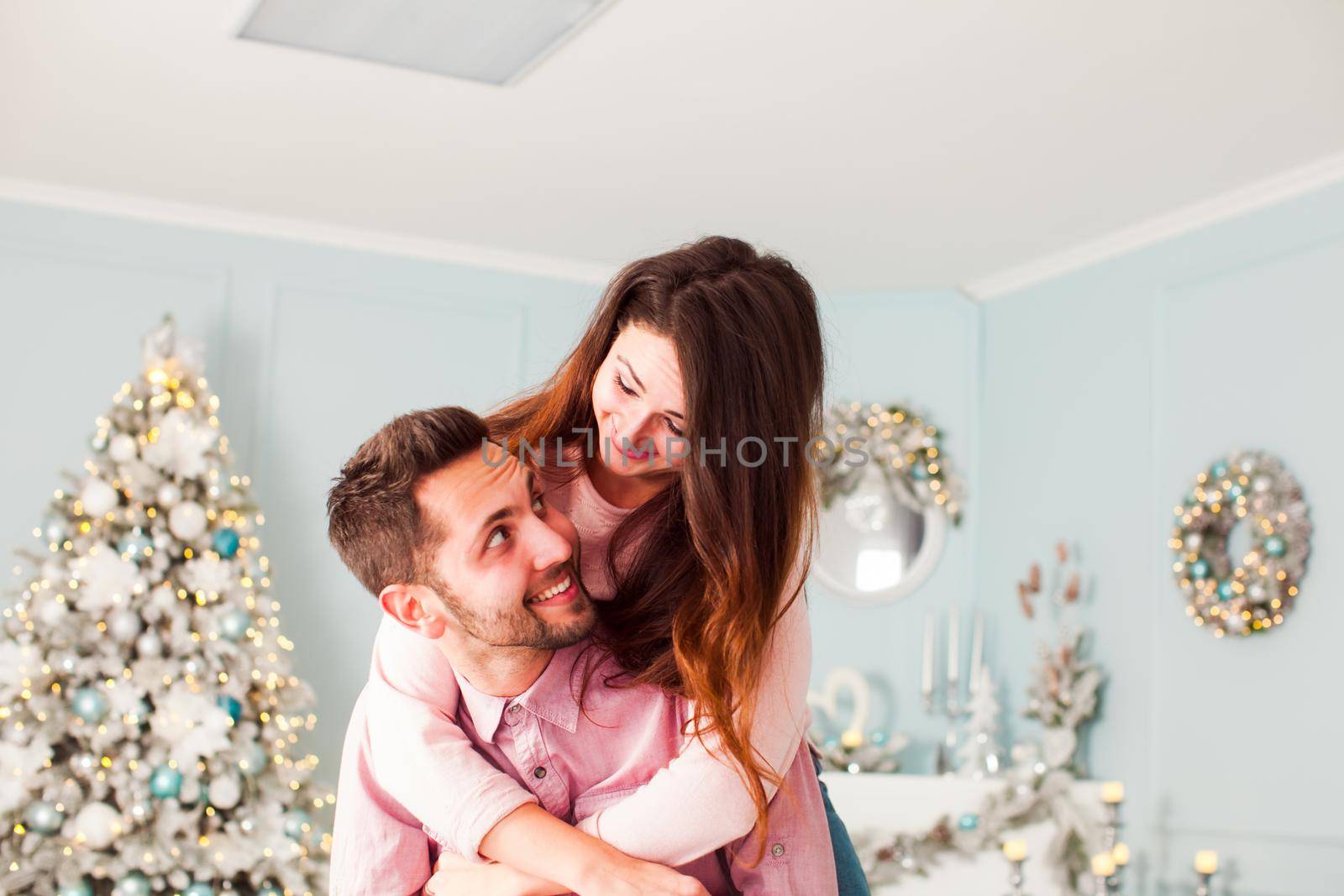 Young happy couple have fun and huggingnear christmas tree by oksix