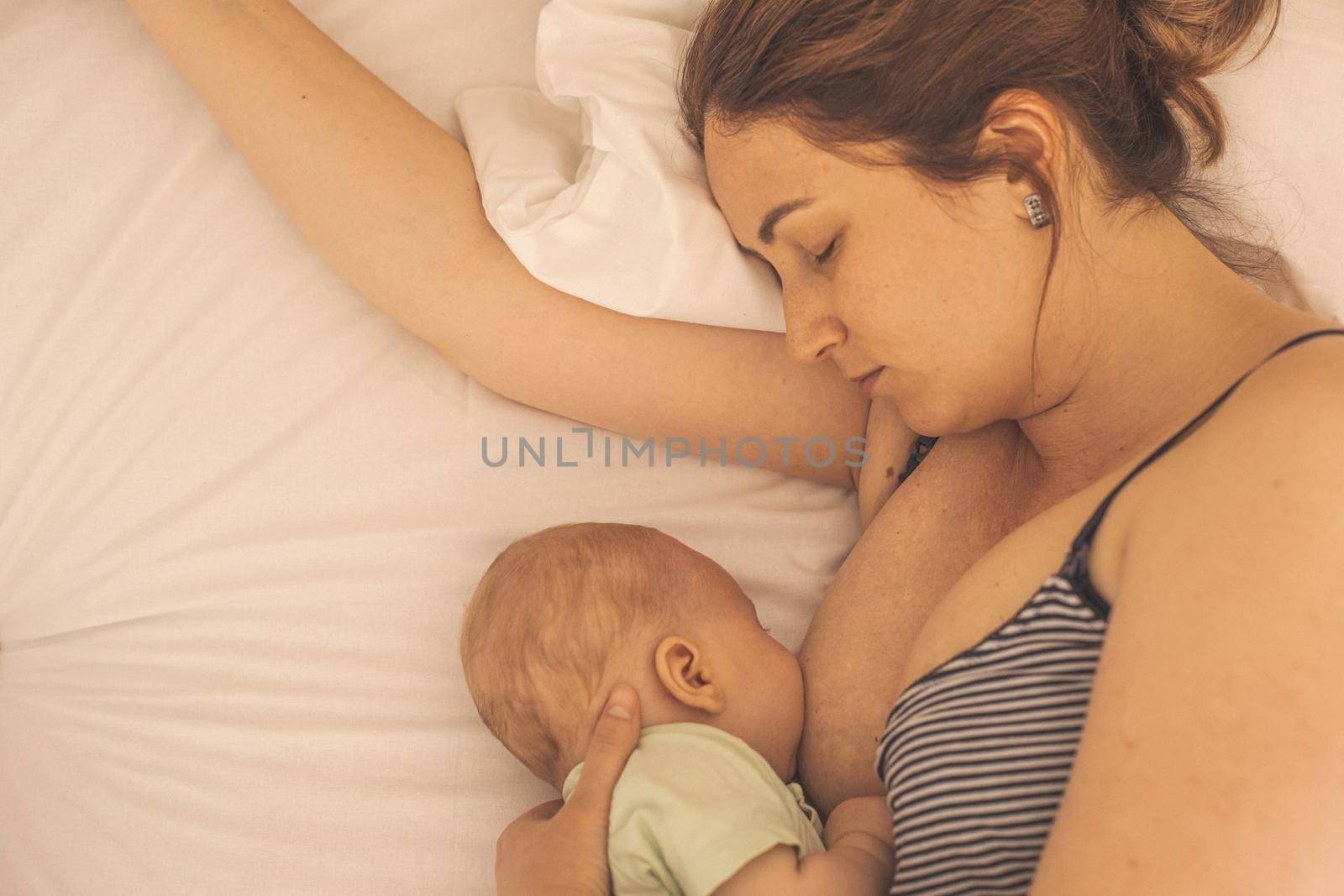 Mother and newborn baby sleep in the bed together