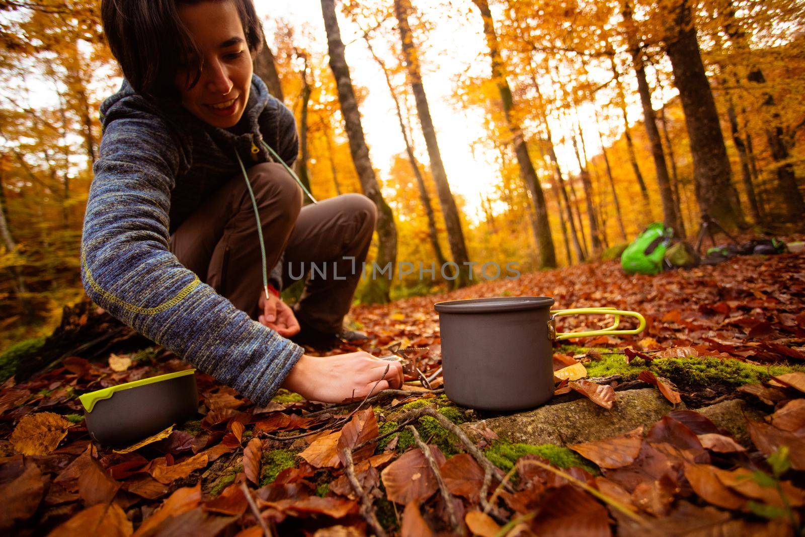 Woman uses portable gas heater and pan for cooking outdoors by oksix