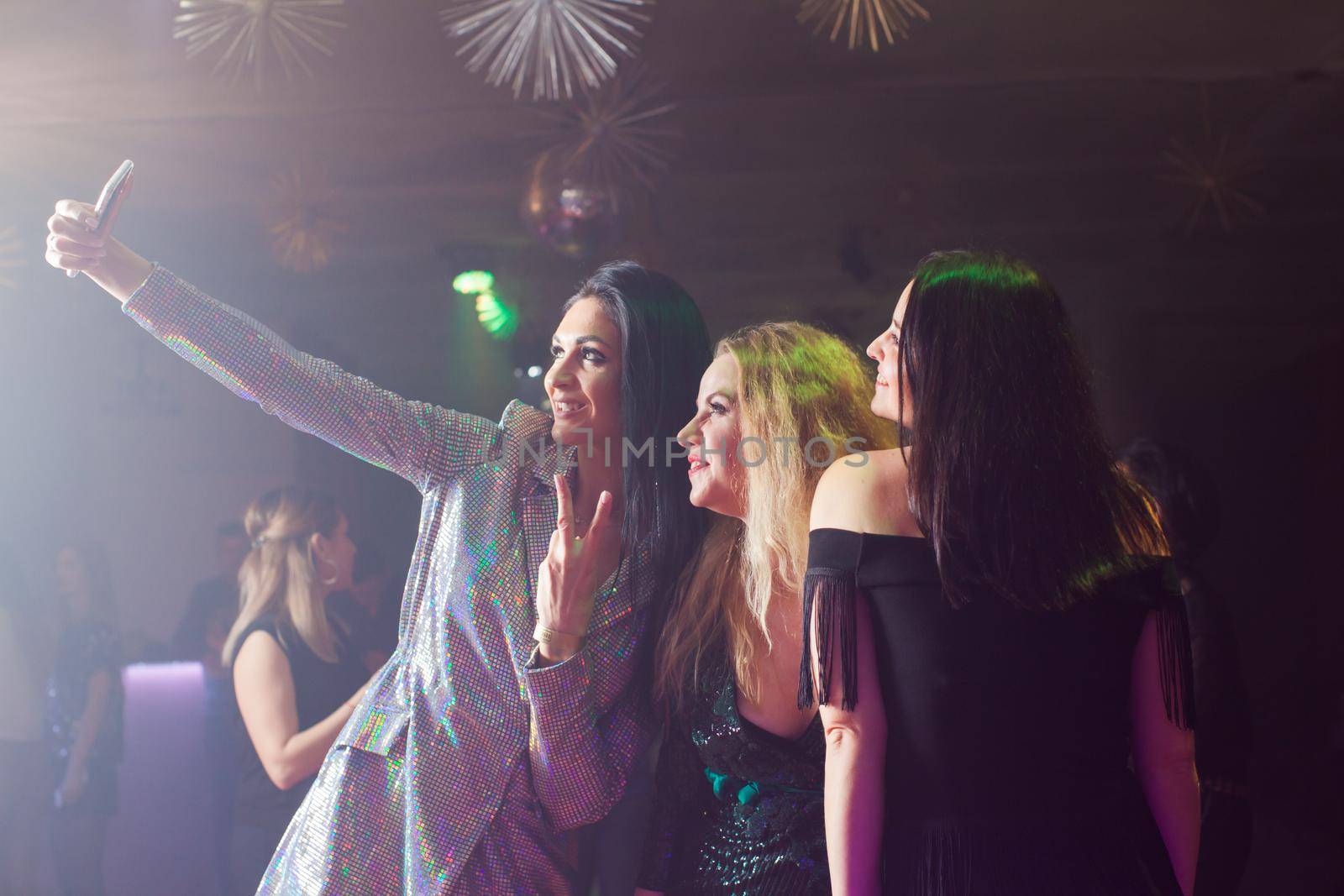 Group of female friends taking selfie on a mobile phone at a nightclub