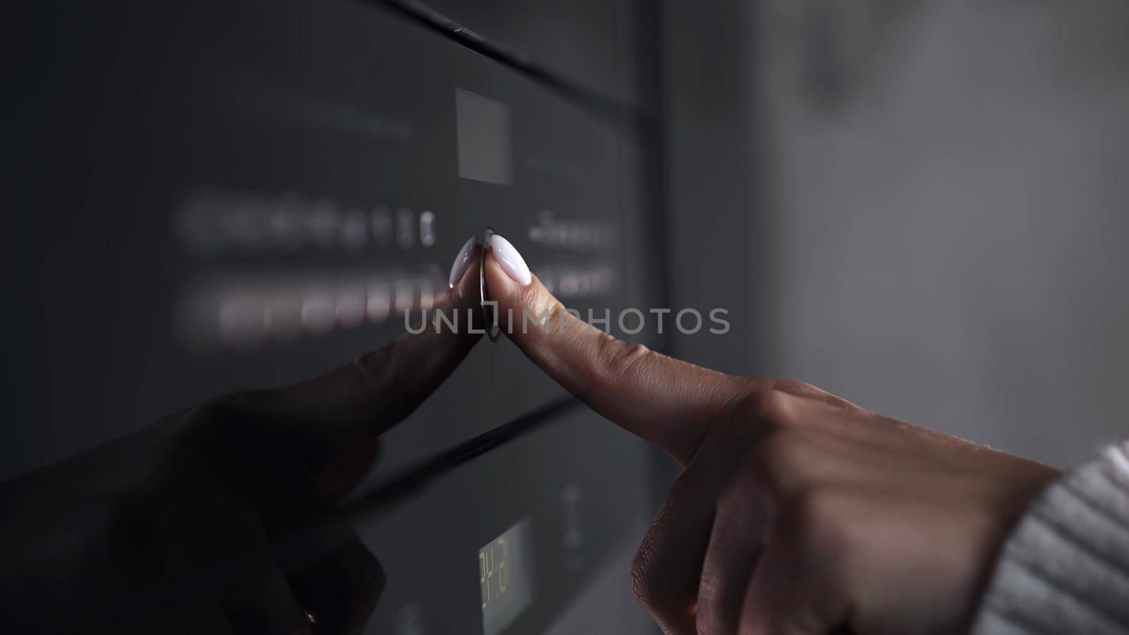 Female finger presses button on modern gas stove or oven. Woman cooking dinner in modern kitchen with equipment. Close-up view. High quality photo