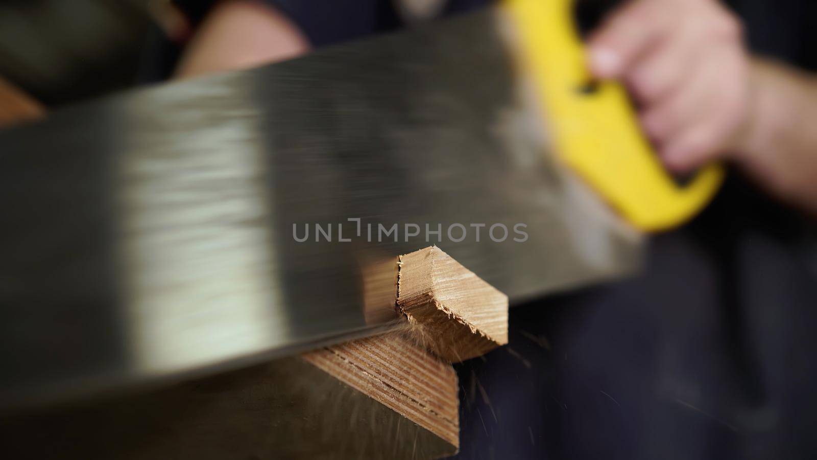 Handwork concept, woodworking workshop. Carpenter saws wooden board with hand jigsaw. Close-up view. . High quality photo