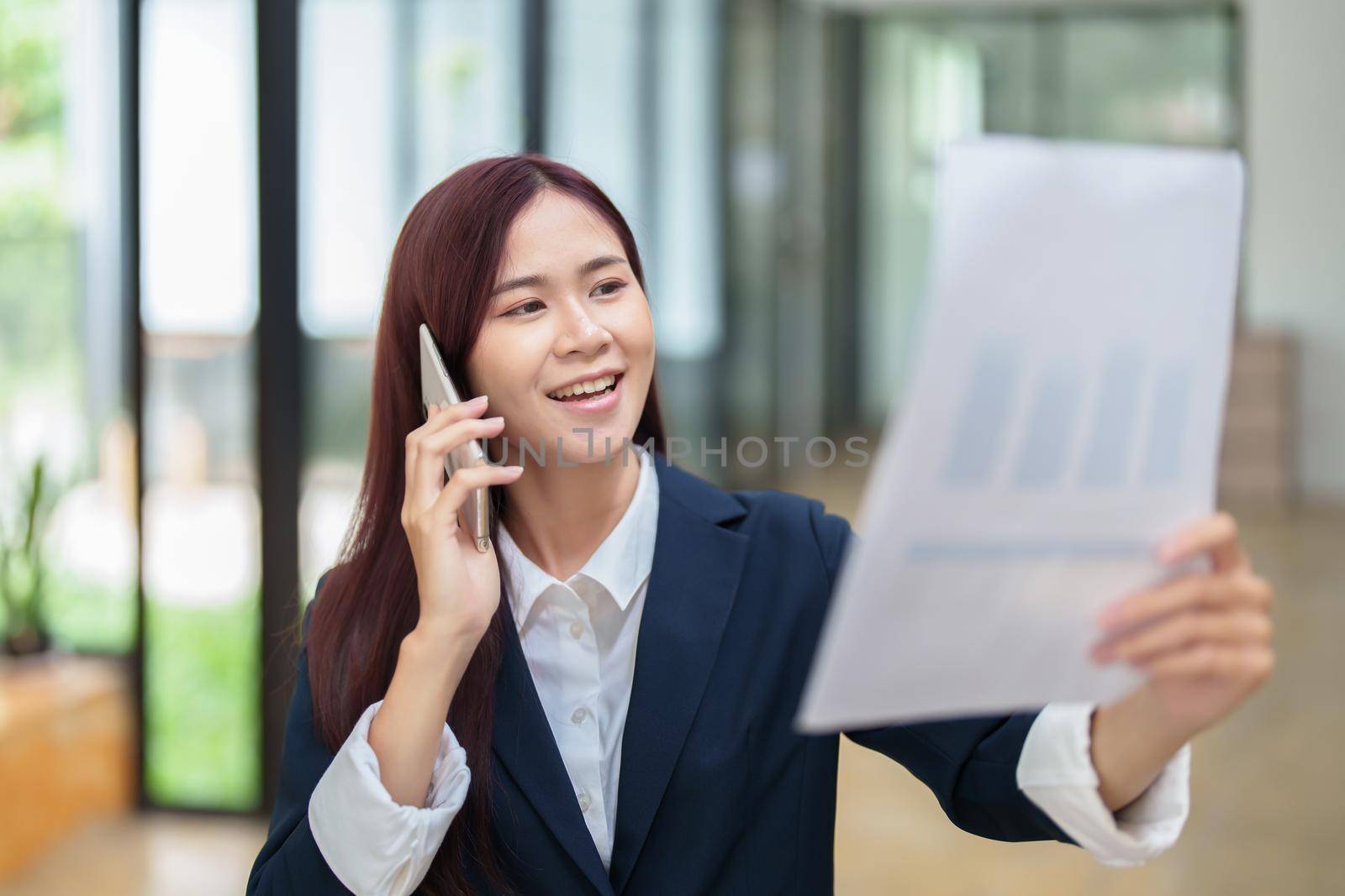 Asian businesswoman using the phone to contact a business partner by Manastrong