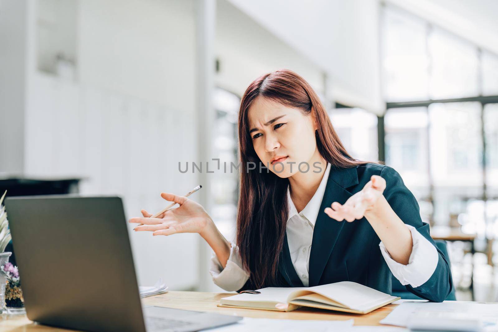 An Asian female employee shows frustration from working on a computer.