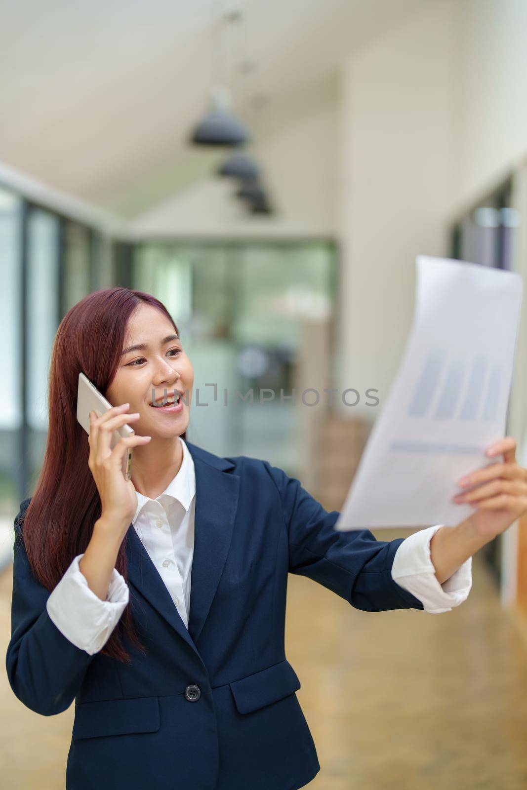 Asian businesswoman using the phone to contact a business partner by Manastrong