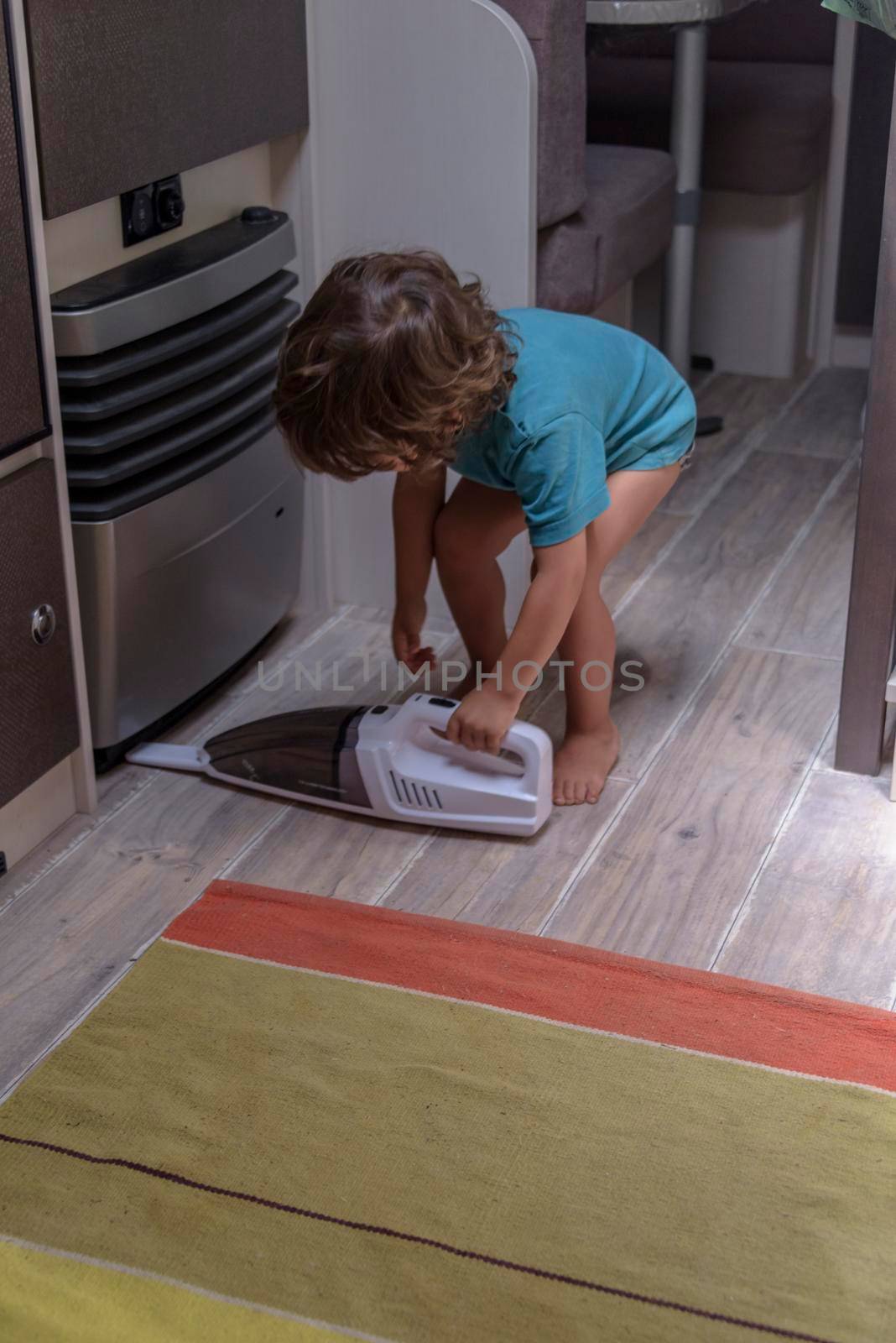 Cute and diligent baby cleans the caravan with a vacuum cleaner. by jbruiz78