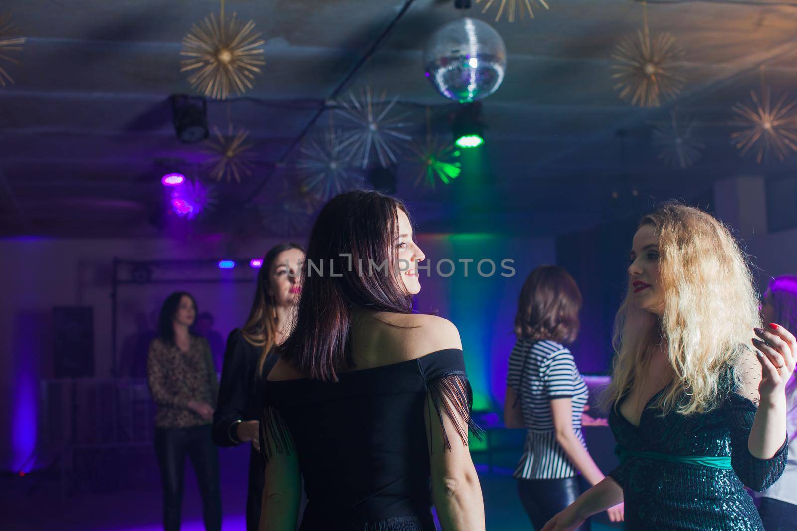 Group of dancing young people enjoying night in club by oksix