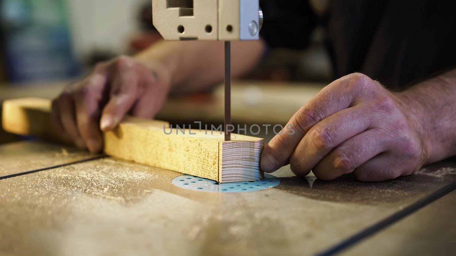 Handwork, carpentry concept, woodworking. Carpenter working in in factory atelier. Joiner labourer cuts wooden plank on jigsaw machine. High quality photo