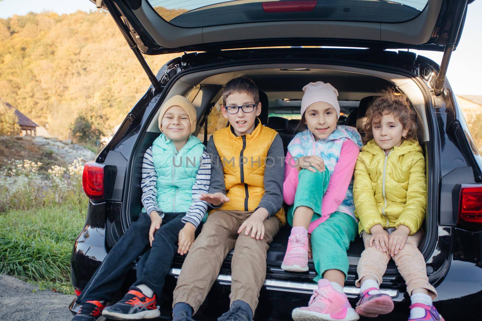 Mom and little boy sitting in hatchback car with mountain background by oksix