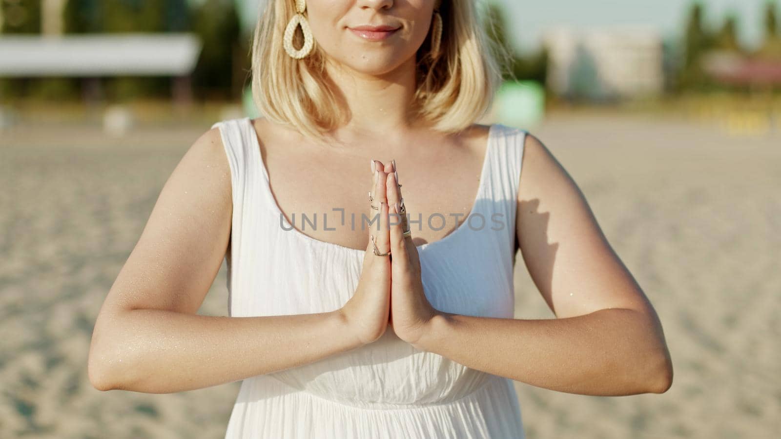 Praying meditating woman, reading mantras, directs thoughts, requests or gratitude to universe. Beach, morning near sea. Spirituality, religion, God concept. High quality photo