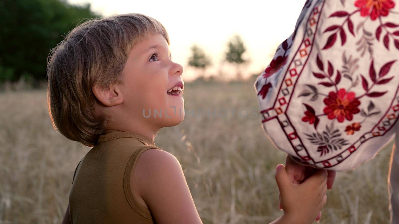 Mom and child holding hands together on wheat field sunset background. Son takes mother hand. Family, trust, love and happiness concept. High quality photo