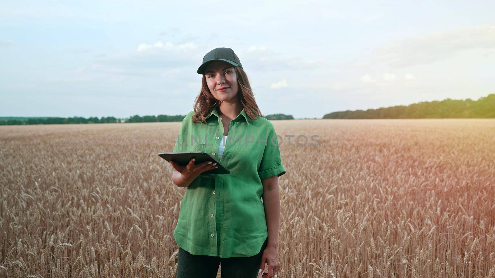 Woman agronomist works in ripe wheat field with digital tablet, checking integrity of ears, growth. Agricultural business, technology, smart eco system, harvest concept. by kristina_kokhanova
