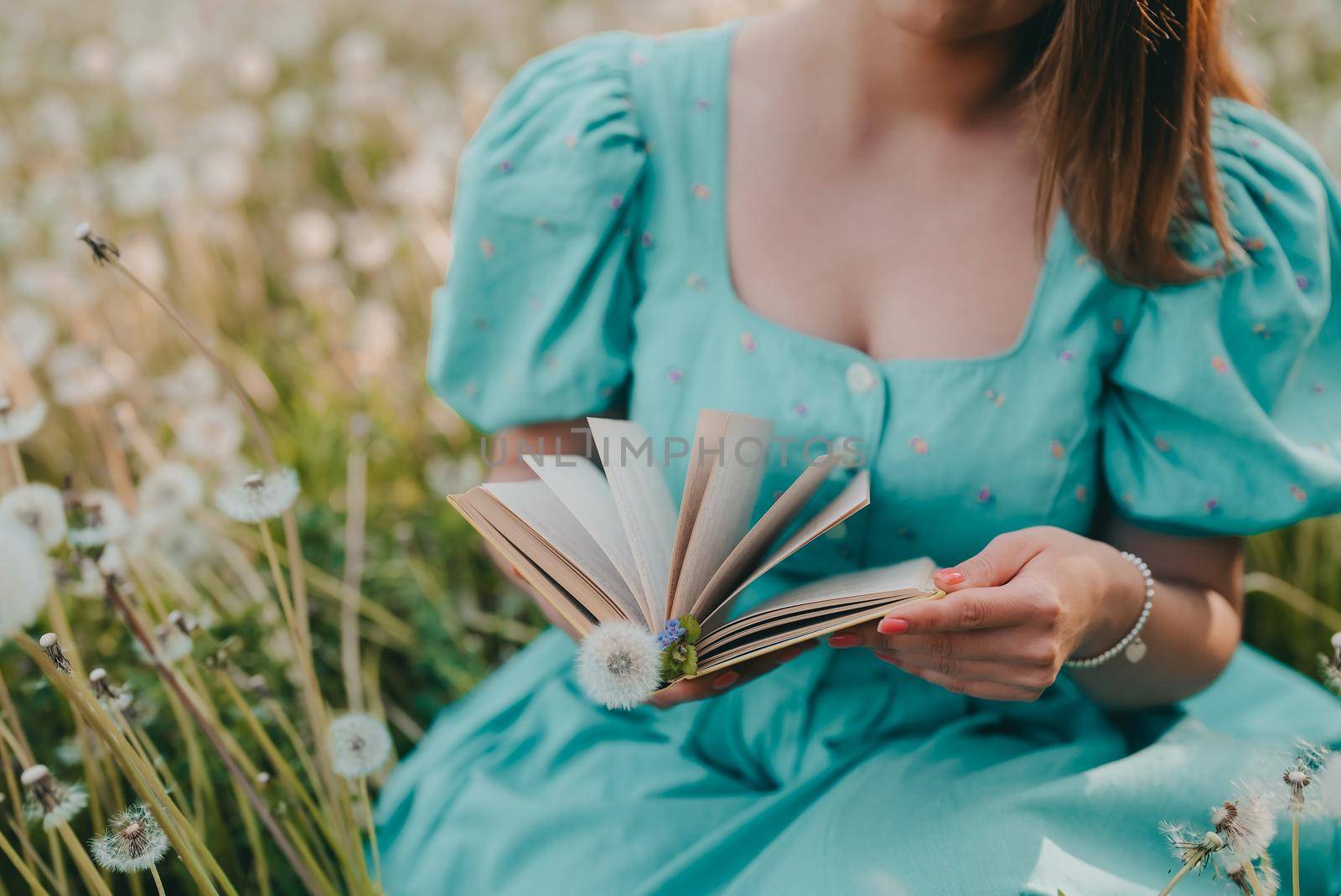 Woman flips through pages of paper book. Lady in retro or vintage dress reading interesting novel while sitting on nature. Atmospheric scene. Education, hobby, entertainment concept.High quality photo
