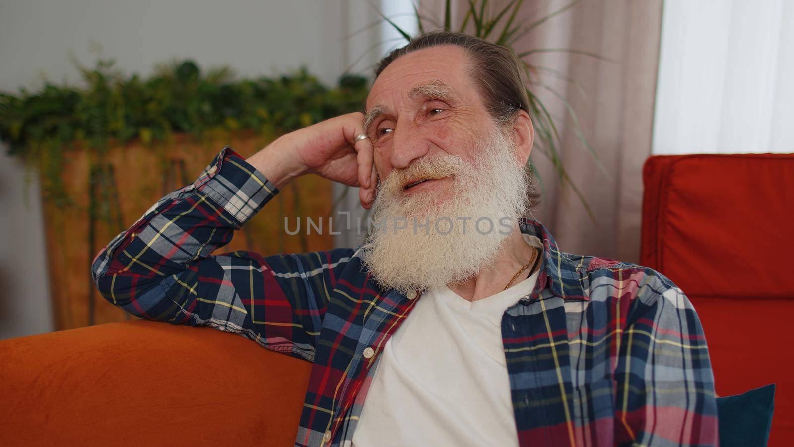 Close-up of happy calm senior old grandfather man pensioner smiling friendly, glad expression looking away dreaming resting, relaxation feel satisfied concept good news sitting on sofa at home room