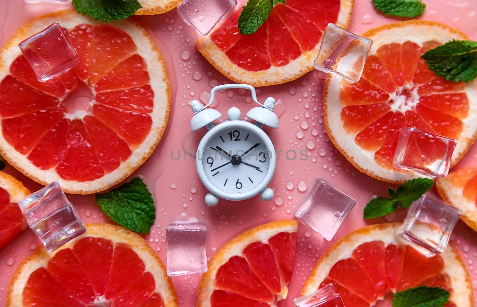 Clock and citruses summer time concept. Selective focus. Food.