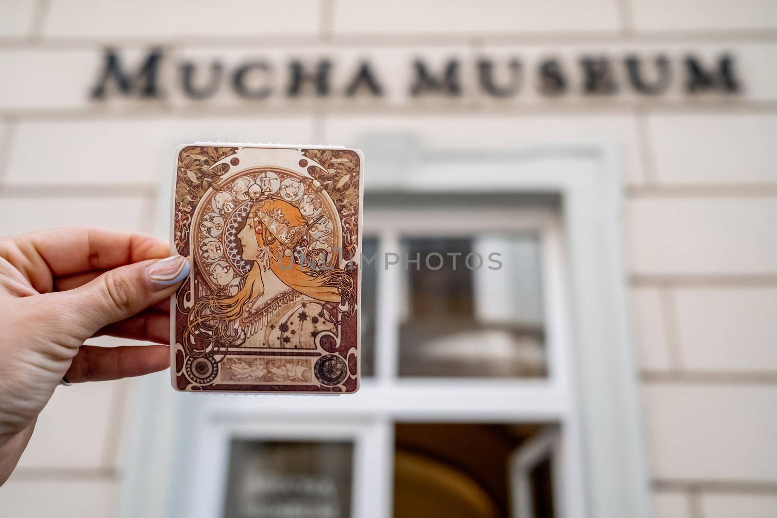 Prague, Czech Republic - July 2022. Alphonse Mucha Museum. Woman holding ticket with Zodiac calendar for La Plume. Gallery dedicated to renowned painter, illustrator, graphic artist. High quality