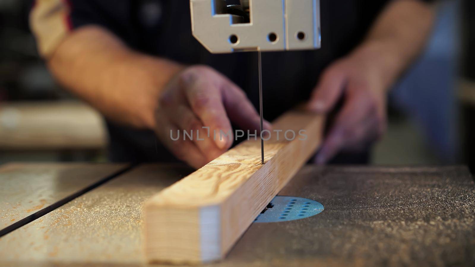 Handwork, carpentry concept, woodworking. Carpenter working in in factory atelier. Joiner labourer cuts wooden plank on jigsaw machine. High quality photo