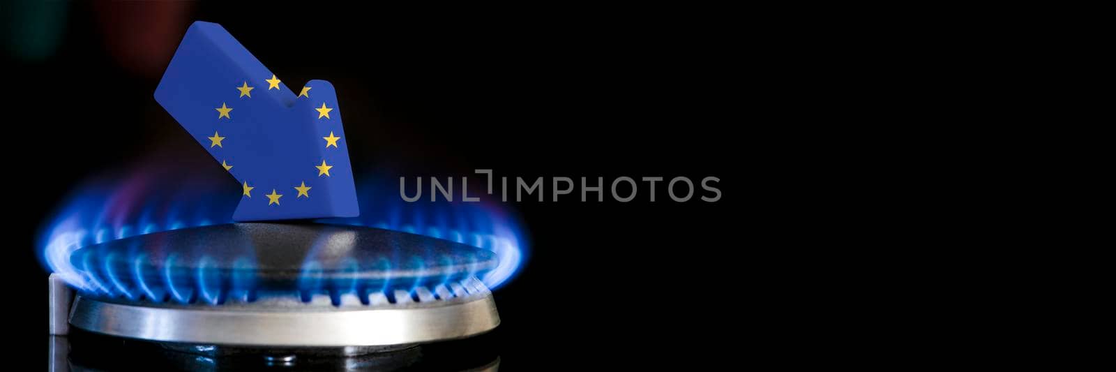 Decreased gas supplies in European Union. A gas stove with a burning flame and an arrow in the colors of the European Union flag pointing down. Concept of crisis in winter and lack of natural gas by SERSOL