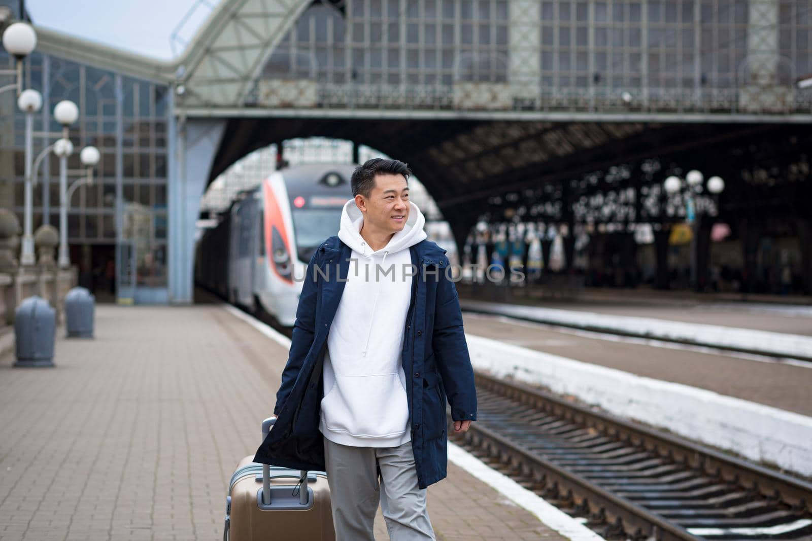 Man asian passenger arrives in nome town, with big suitcase, tourist at train station