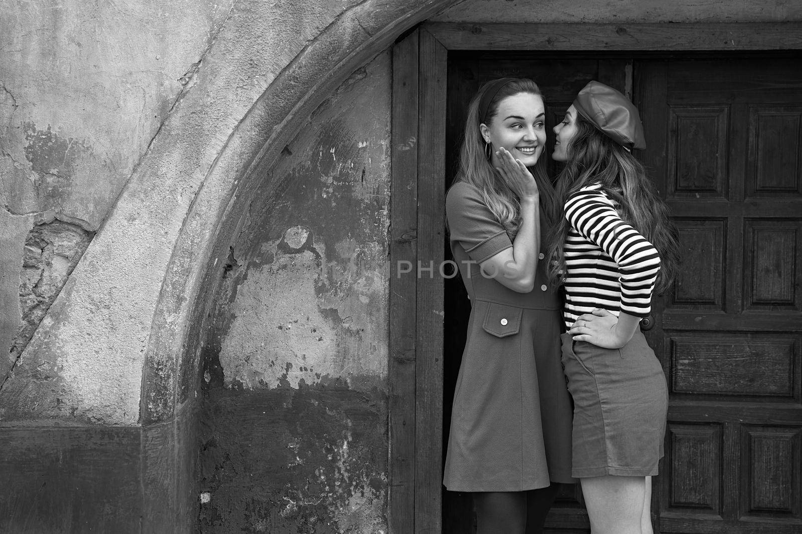 Young beautiful girls dressed in retro vintage style enjoying the old european city summertime lifestyle. Chatting in the street. Black and white.