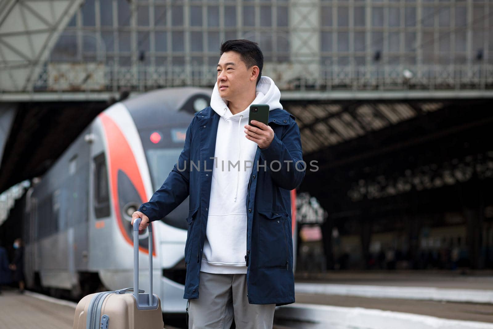 Man asian passenger arrives in nome town, with big suitcase, tourist at train station