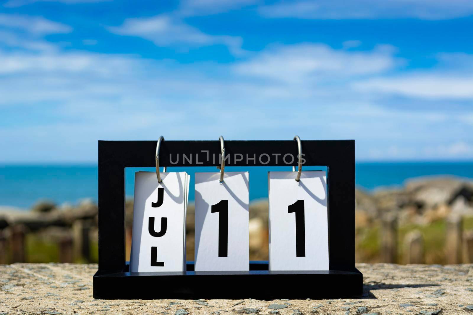 Jul 11 calendar date text on wooden frame with blurred background of ocean. Calendar date concept.